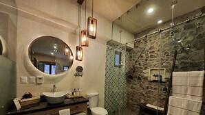 Un bagno moderno con un grande specchio, un lavandino rotondo e una cabina doccia in vetro.
