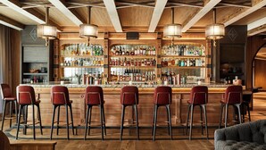 A bar area with wooden bar stools, a variety of liquor bottles, and pendant lighting. - Auberge Resort 5 Star Residence (Mountain Village)