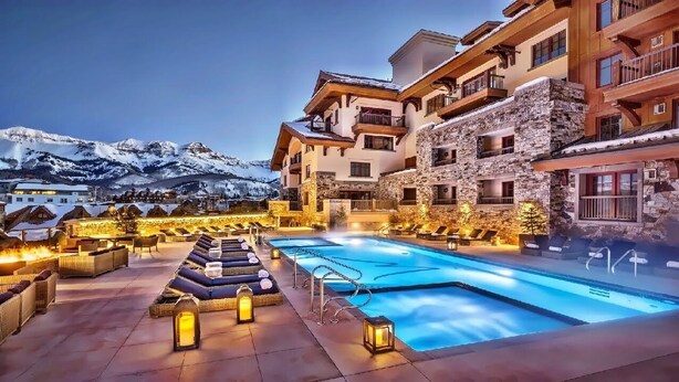 A hotel with a pool, lounge chairs, and a view of snow-capped mountains. - Auberge Resort 5 Star Residence (Mountain Village)