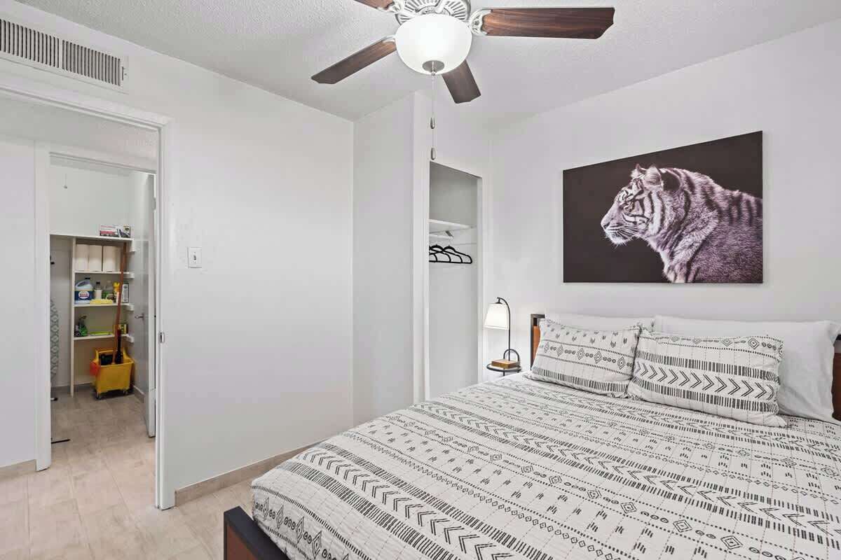 A bedroom with a bed, a ceiling fan, a tiger artwork, and a closet.