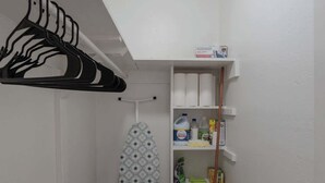 A laundry room with a drying rack, ironing board, shelves with cleaning supplies, and a mop cart. - Sleek 2-Bed 1-Bath Home • Near Fort Bliss (El Paso)