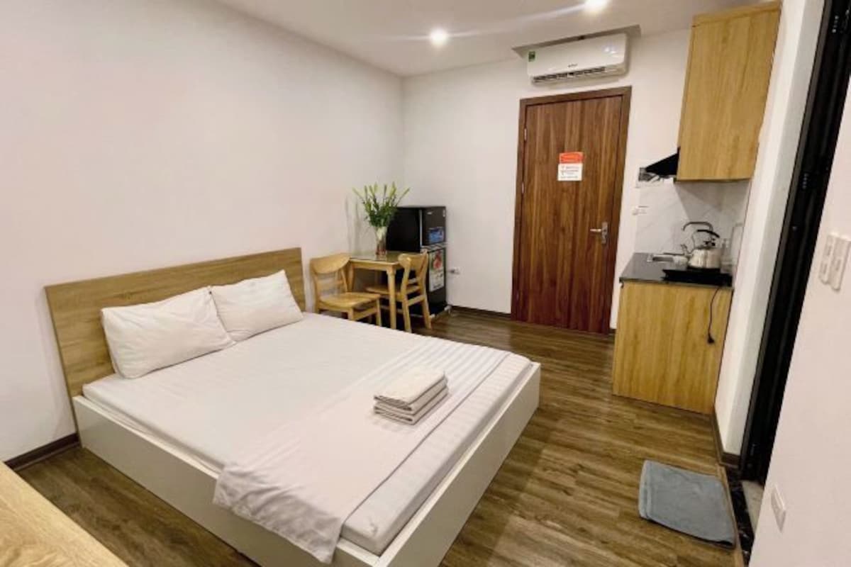 Une chambre comprenant un lit, un bureau, une chaise et un coin cuisine.