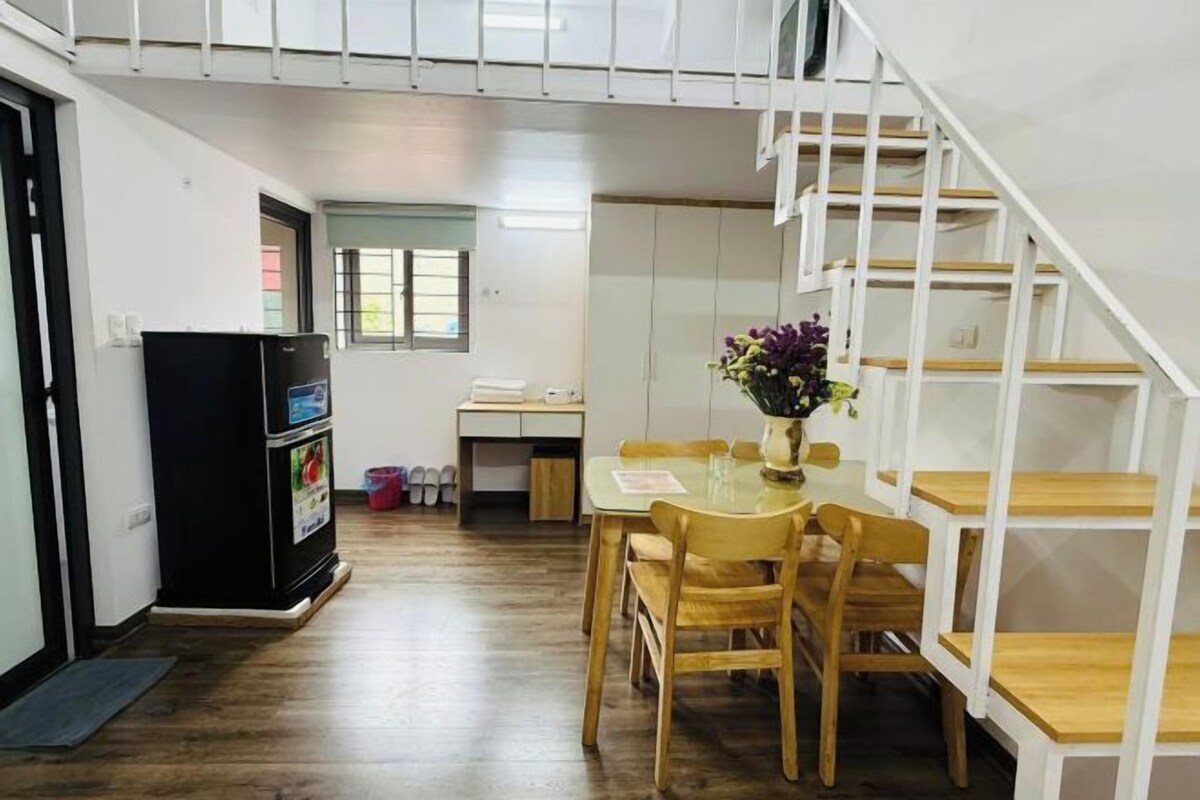 Un espacio habitable compacto con comedor, kitchenette y una escalera.