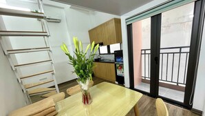Una cocina moderna con armarios de madera, una mesa de comedor con sillas, un florero con flores y una puerta corrediza de vidrio al balcón.