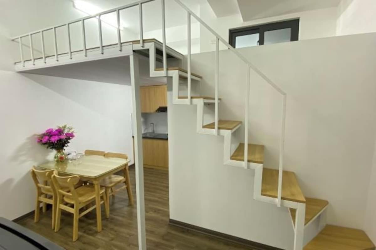 Un espace de vie compact comprenant un coin repas, une cuisine et un escalier.