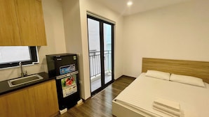 Habitación de hotel con cama, minibar, lavamanos y balcón con vistas.