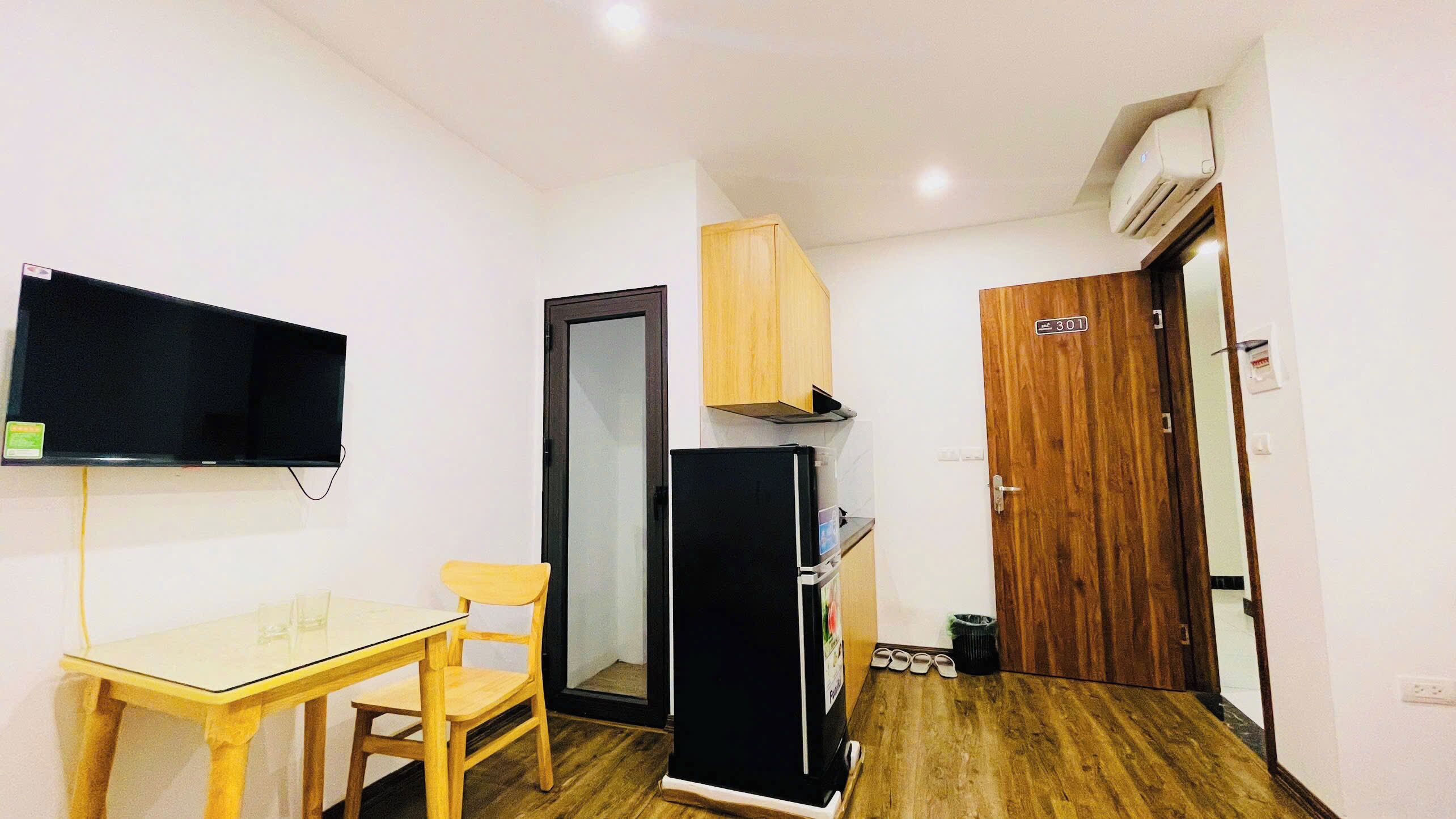 Una cocina compacta con refrigerador, microondas y un mueble de madera.