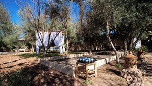 A rustic outdoor area with a wooden bench, a stone wall, and a small table with decorative items.
