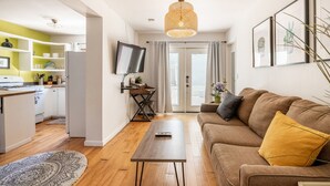 Ein modernes Wohnzimmer mit einer Couch, einem Couchtisch und einem an der Wand befestigten Fernseher.