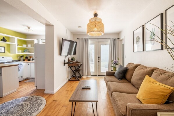 A modern living room with a sofa, a coffee table, and a TV mounted on the wall. - South Park 1 House 2 Full Apartments w Laundry (San Diego)