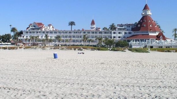 Ein Strandhotel mit einem markanten Turm, dessen Dach rot ist, und zahlreichen Balkonen.