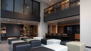 A modern hotel lobby with a mezzanine level, seating areas, and a reception desk. - New, comfortable, excellent location. In Barra: beach, pool and carnival (Barra Salvador)