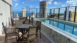 A rooftop terrace with a pool, outdoor furniture, and a city view. - New, comfortable, excellent location. In Barra: beach, pool and carnival (Barra Salvador)