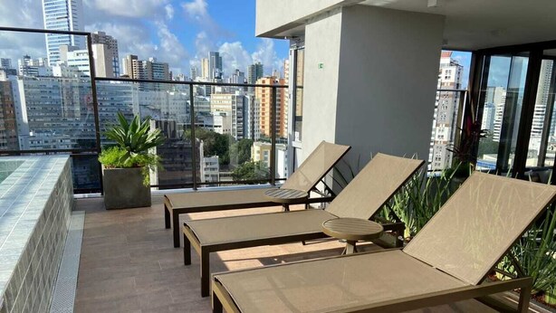 A rooftop terrace with lounge chairs and a small potted plant. - New, comfortable, excellent location. In Barra: beach, pool and carnival (Barra Salvador)