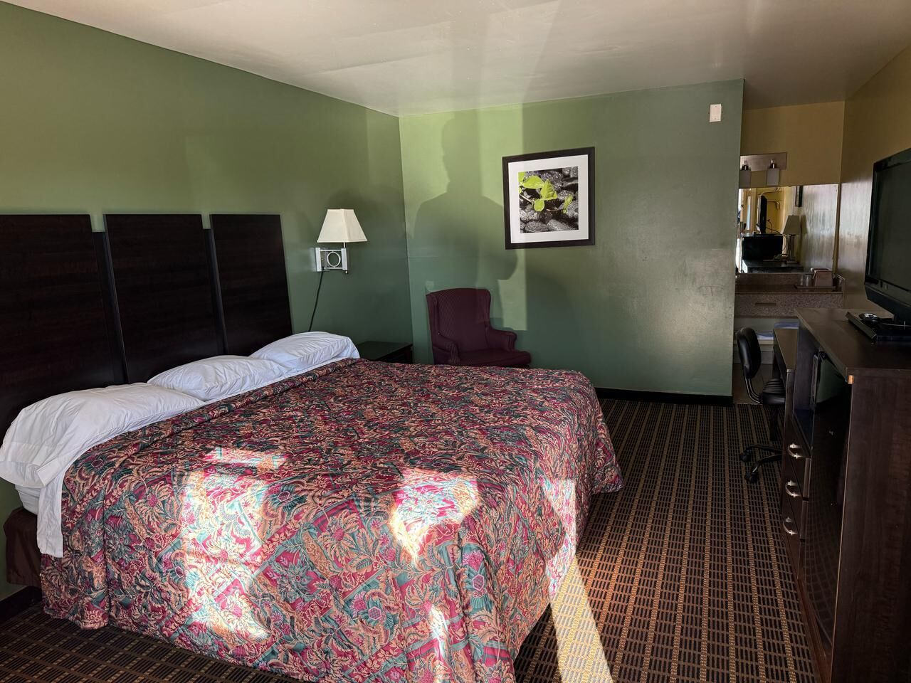 Une chambre d’hôtel avec un grand lit, un bureau, une chaise et un téléviseur.
