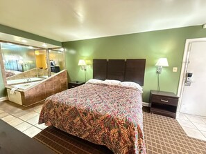Una camera d'albergo con un letto grande, un bagno con vasca e uno specchio.