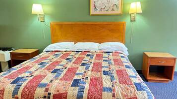 Une chambre d’hôtel avec une tête de lit en bois, une couvre-lit matelassée, deux lampes de chevet, une table de chevet et une petite armoire en bois.