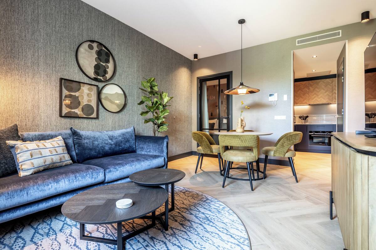 Ein modernes Wohnzimmer mit einem blauen Sofa, einem Couchtisch und einem Essbereich mit Stühlen.