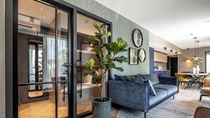 A modern living room with a blue sofa, a potted plant, and a glass door leading to a kitchen. - BizStay Delft  (Delft)