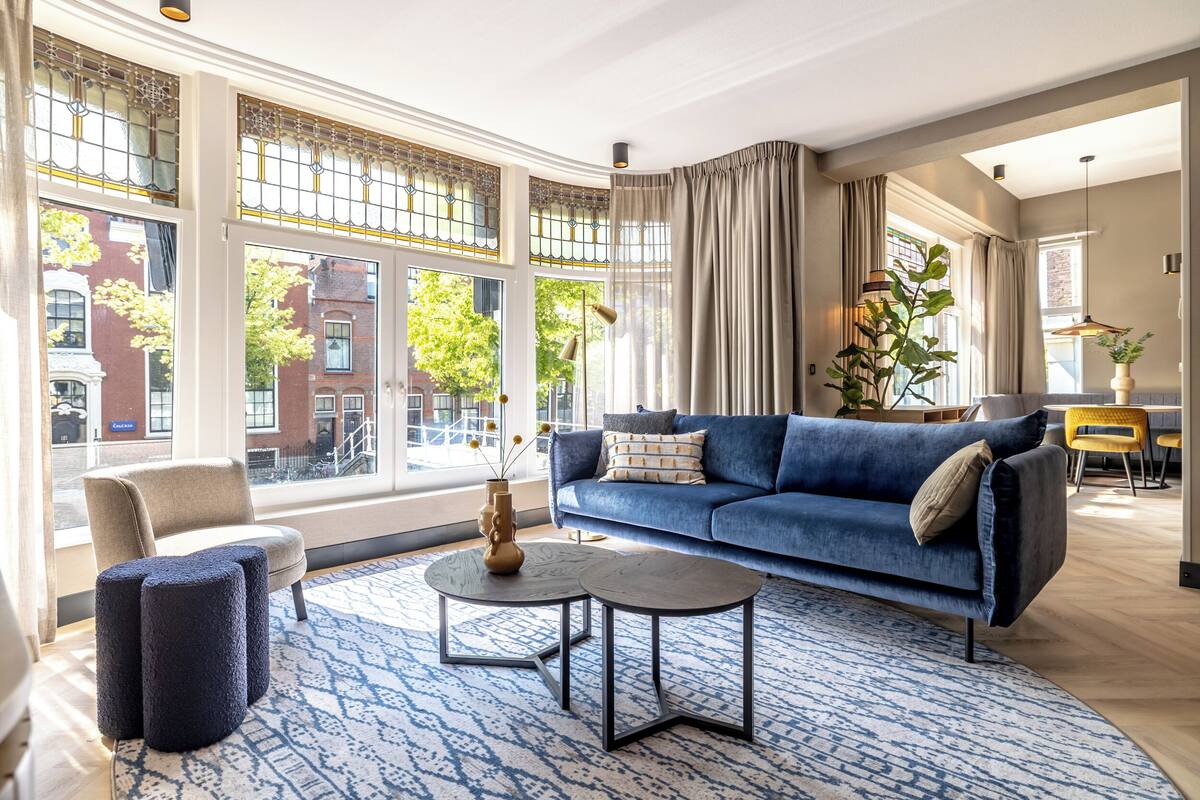 Ein modernes Wohnzimmer mit einem blauen Sofa, einem runden Couchtisch und einem gemusterten Teppich.