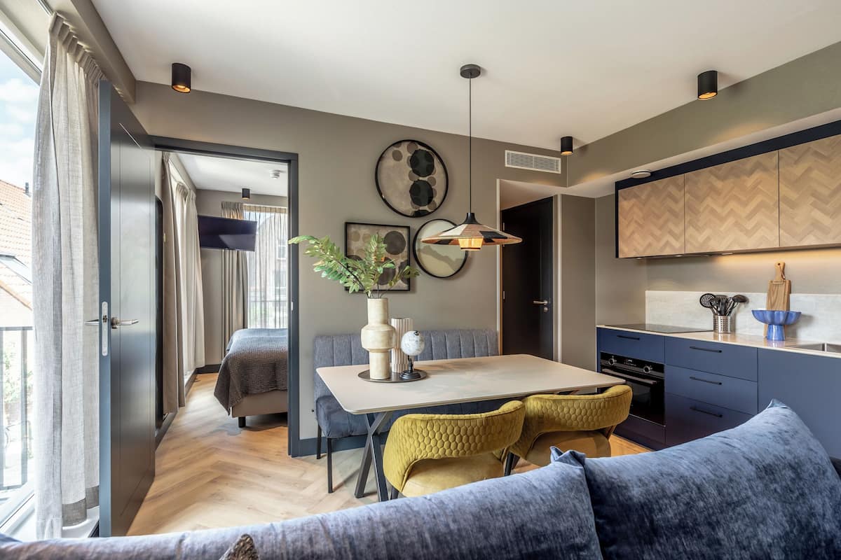Eine moderne Küche mit Essbereich, inklusive eines großen Tisches, gelber Stühle und einem blauen Sofa.