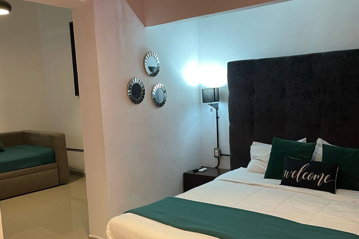 Un dormitorio con cama, mesitas de noche, lámpara y adornos en la pared.