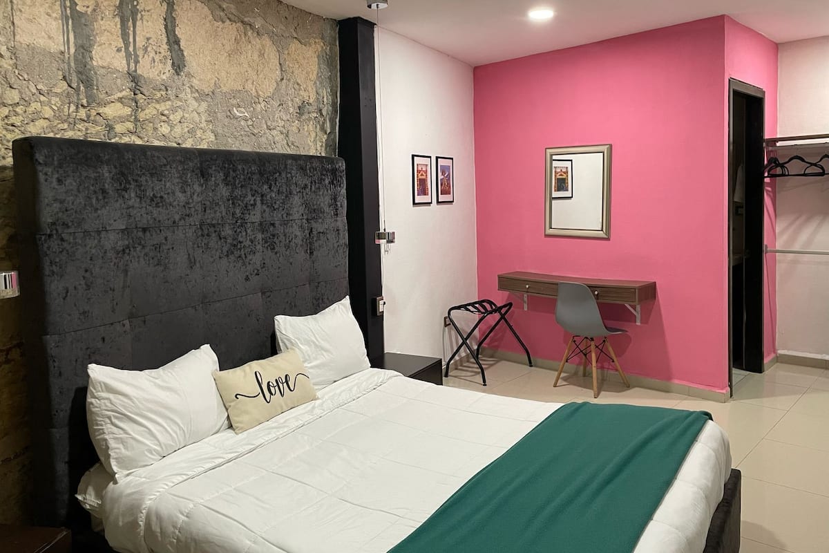 Un dormitorio con cama, escritorio y silla.