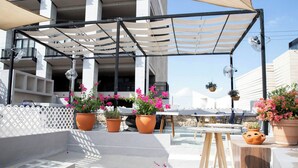 Un patio al aire libre con una pérgola, plantas en macetas y una mesa.
