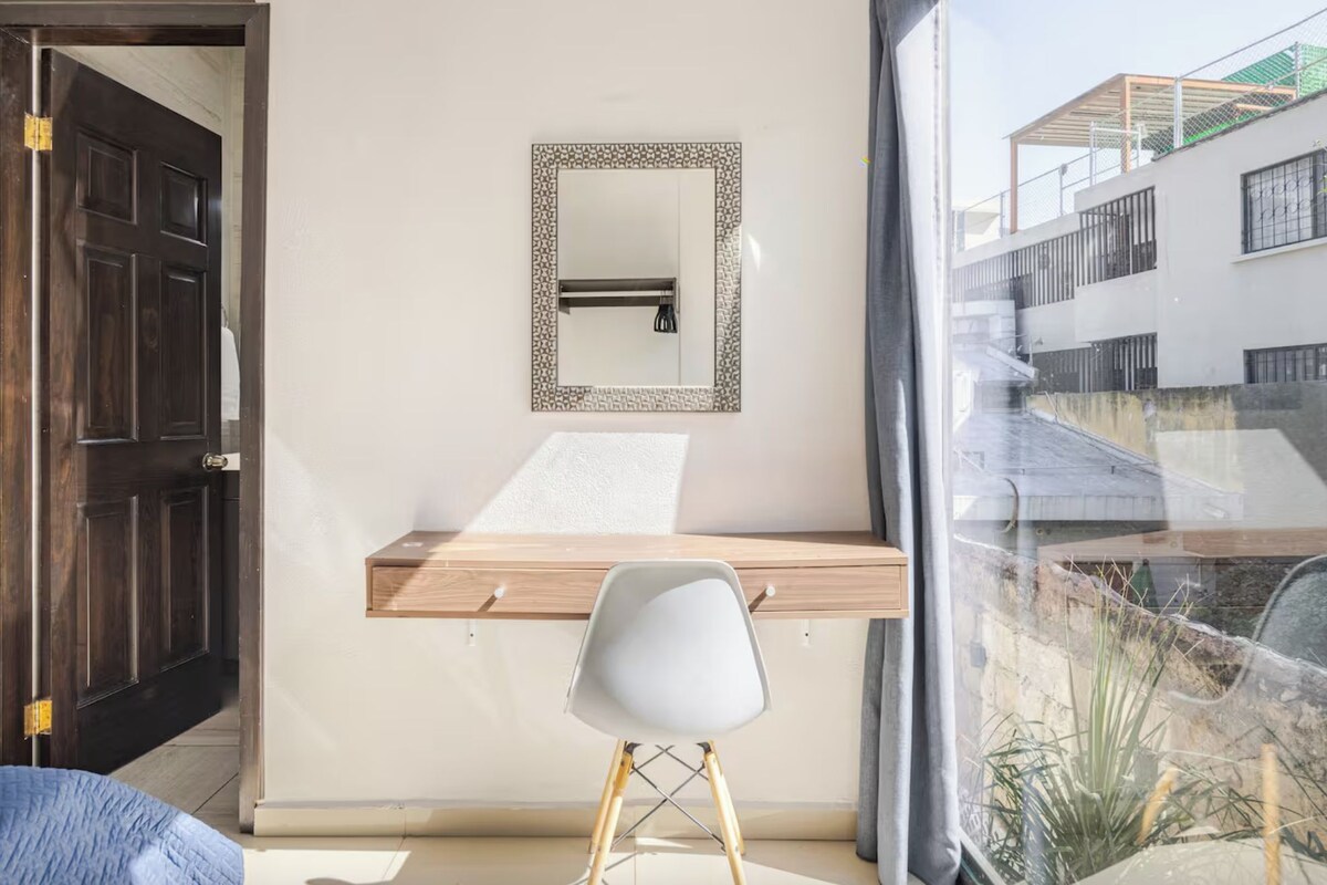 Une pièce comprenant un bureau, une chaise et un miroir au mur.