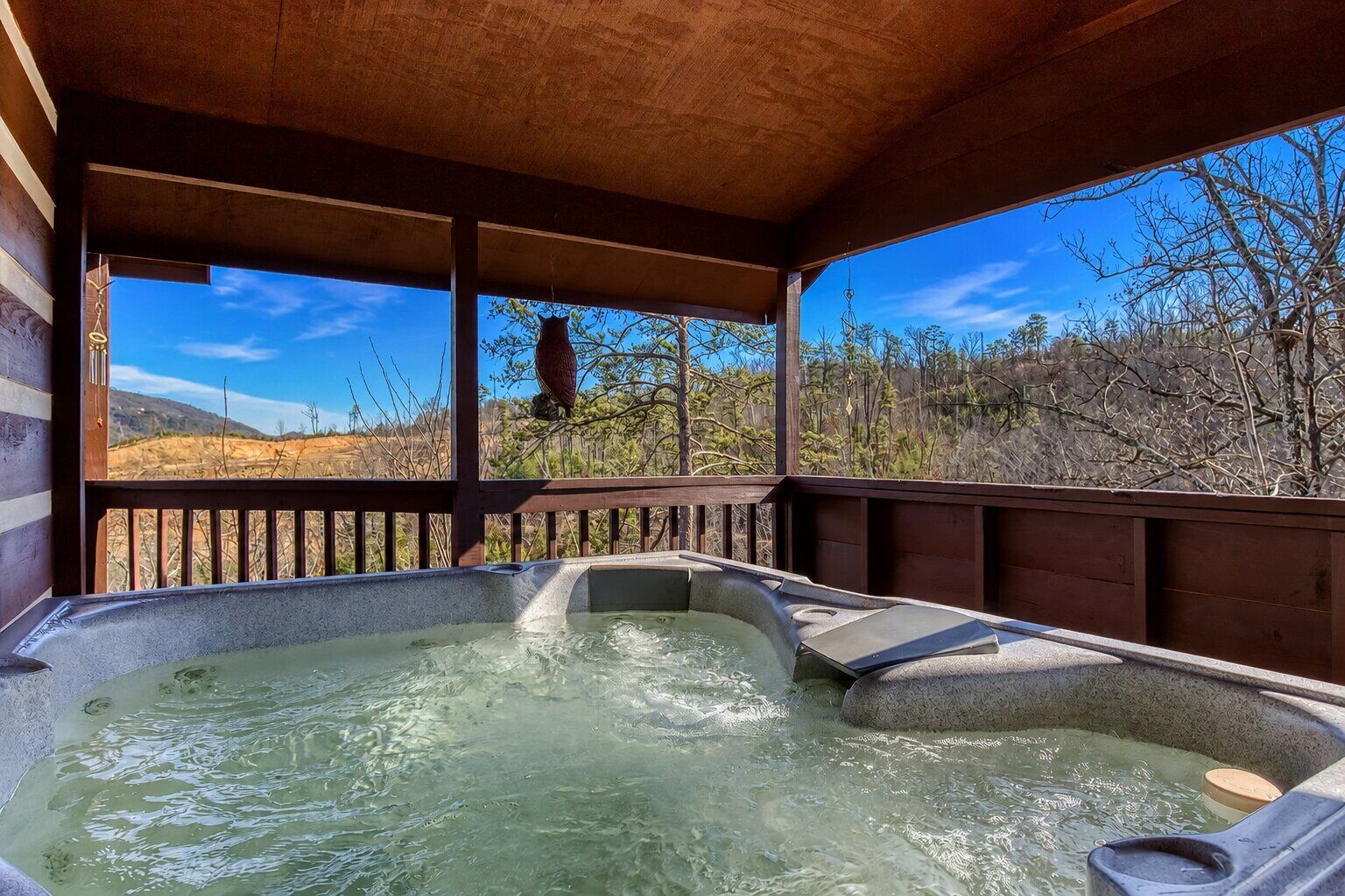 A hot tub with a wooden deck and a view of a forested landscape.