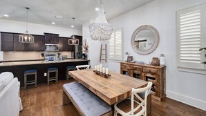 A modern kitchen with dark cabinets, a wooden island, and pendant lighting.