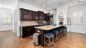 A modern kitchen with dark wood cabinets, a granite countertop, and a central island with bar stools.