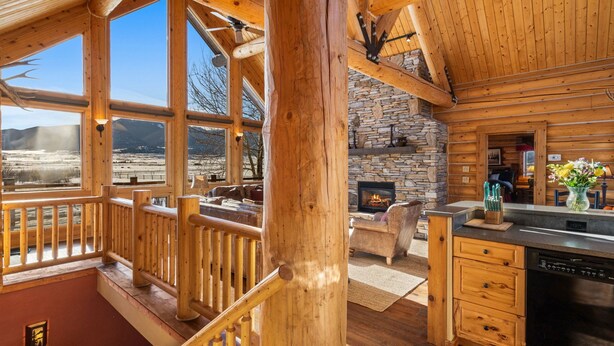 Eine geräumige Holzhütte mit großen Fenstern, einem steinernen Kamin und einem gemütlichen Wohnbereich.
