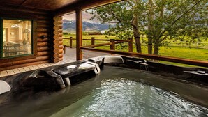 Ein Whirlpoolbereich mit Holzterrasse und Blick auf Berge und Grünland.