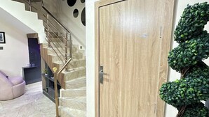 A staircase with a wooden door and a green artificial plant beside it. - Zinq Bridge Aparments (Abuja)