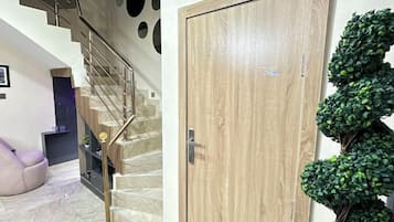 A staircase with a wooden door and a green artificial plant beside it.