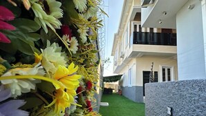 A building with a vertical garden, a stone wall, and a green lawn. - Zinq Bridge Aparments (Abuja)