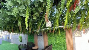 An outdoor seating area with artificial grass, wicker furniture, and hanging plants. - Zinq Bridge Aparments (Abuja)