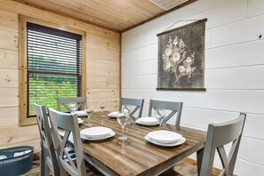 Enjoy meals in this cozy cabin-style dining area with a table for four, surrounded by natural views and a touch of local art.