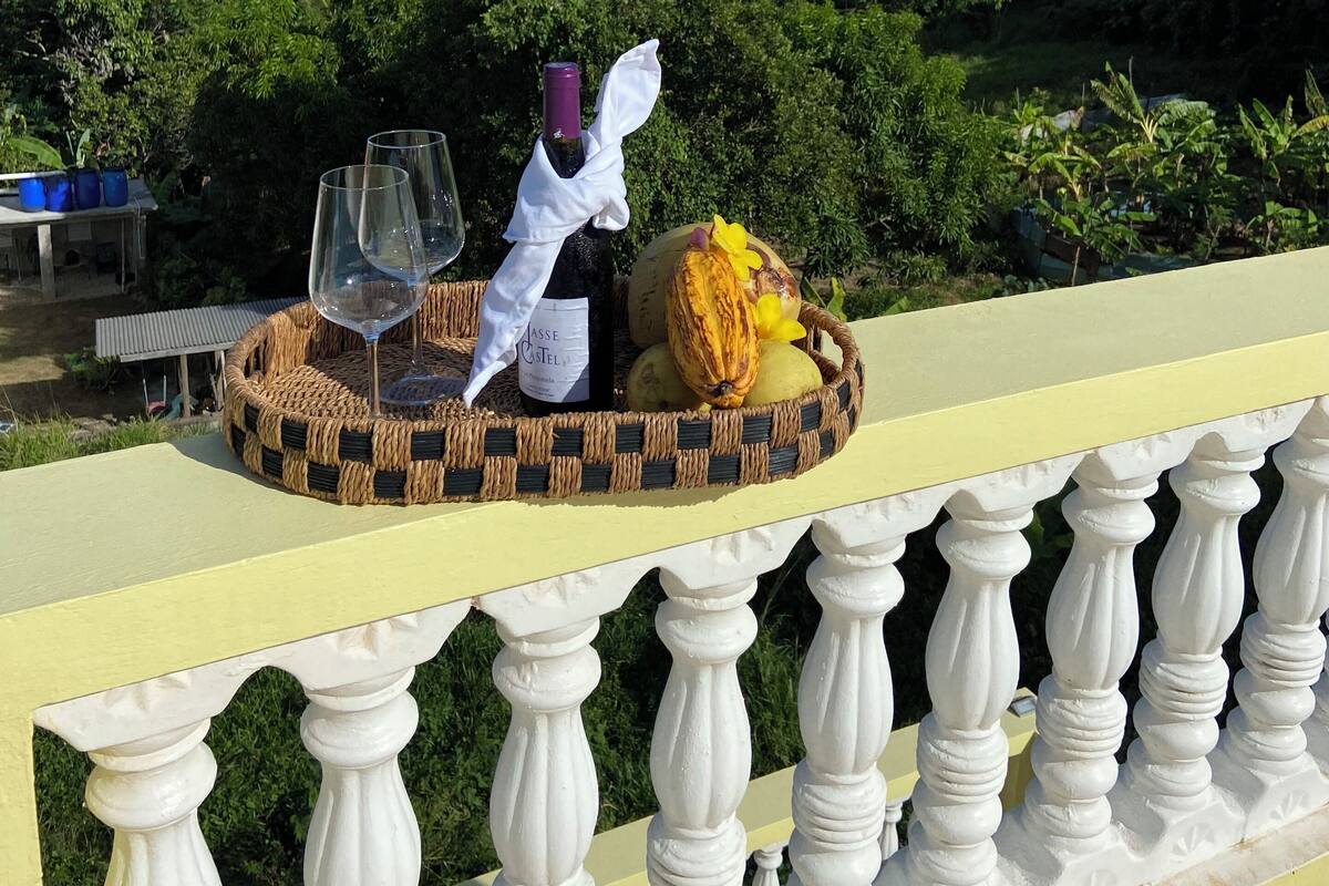 Ein Balkon mit einem Korbtablett, das eine Weinflasche, ein Glas und Früchte trägt.