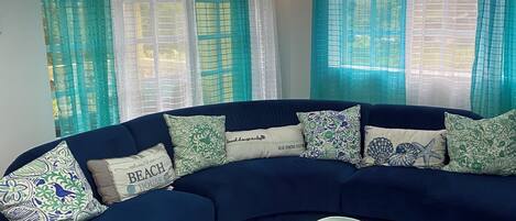 A living room with a dark blue sofa, patterned cushions, and a glass coffee table.