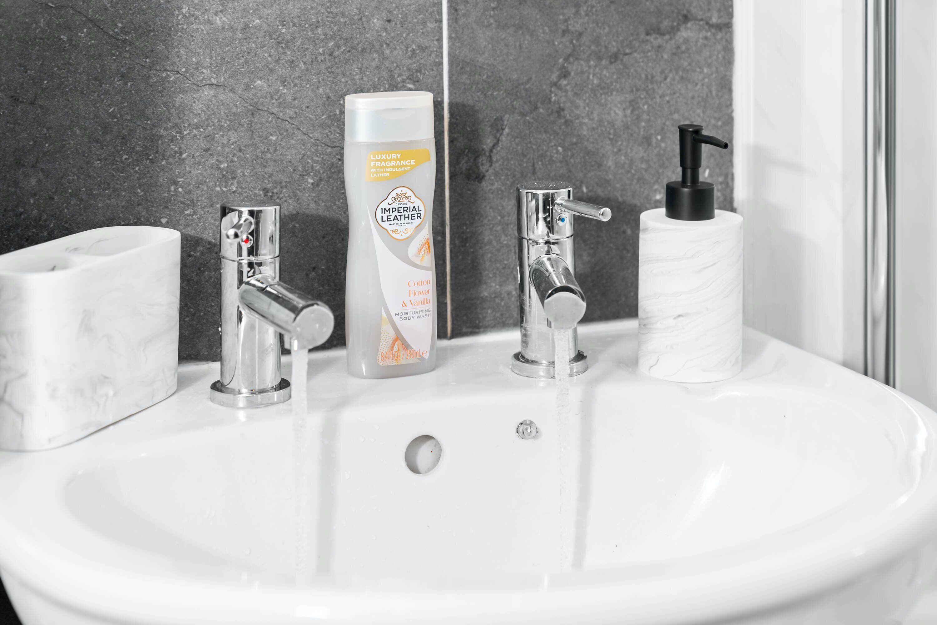 A bathroom sink with a marble basin, a soap dispenser, and a paper towel holder.