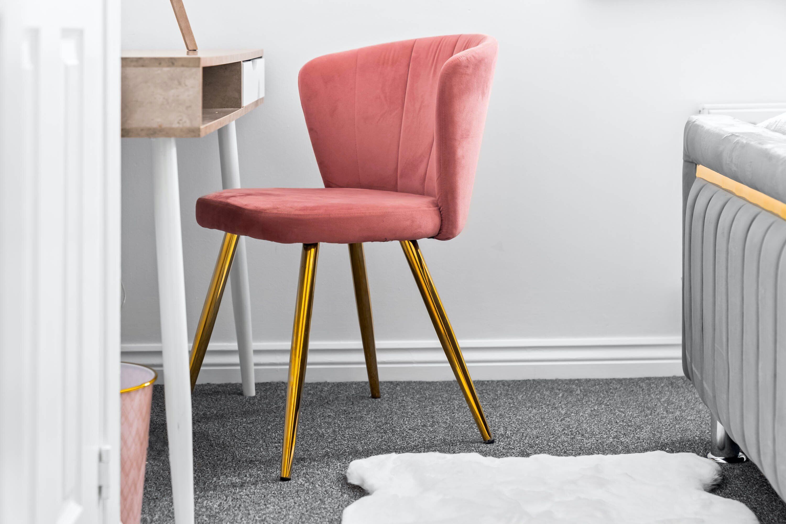 A room with a pink chair, a grey sofa, a white rug, and a small wooden table.