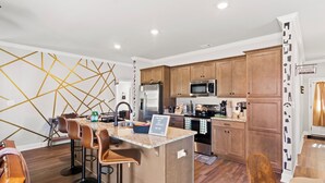 Eine moderne Küche mit Holzschränken, einem Edelstahlkühlschrank und einer eingebauten Mikrowelle.