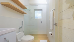 A modern bathroom with a toilet, glass shower enclosure, and a towel rack. - Reef Townhouse Tides (T39) (Chame)