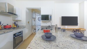 A modern kitchen with a built-in oven, microwave, and washing machine. - Reef Townhouse Tides (T39) (Chame)
