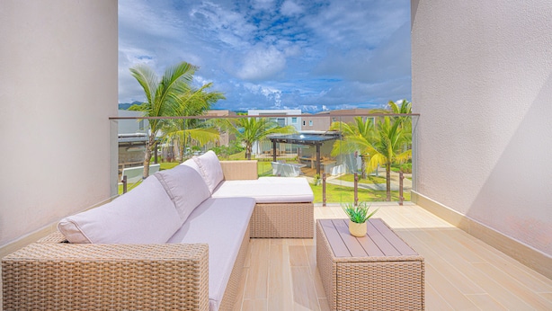A balcony with a wicker sofa, a small table, and a potted plant. - Reef Townhouse Tides (T39) (Chame)