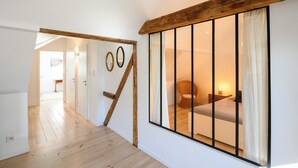 A bedroom with a large window, wooden beams, and a bed with a nightstand. - Superb loft 10min from Strasbourg (Eckbolsheim)