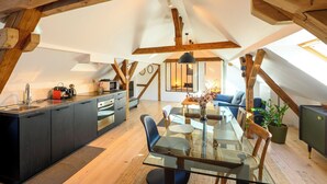 A modern loft with exposed wooden beams, a kitchen with a central island, a dining area with a glass table, and a cozy seating area with a blue sofa. - Superb loft 10min from Strasbourg (Eckbolsheim)