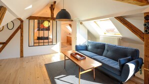 A cozy loft apartment with a high ceiling, wooden beams, a blue sofa, a wooden coffee table, and a skylight. - Superb loft 10min from Strasbourg (Eckbolsheim)